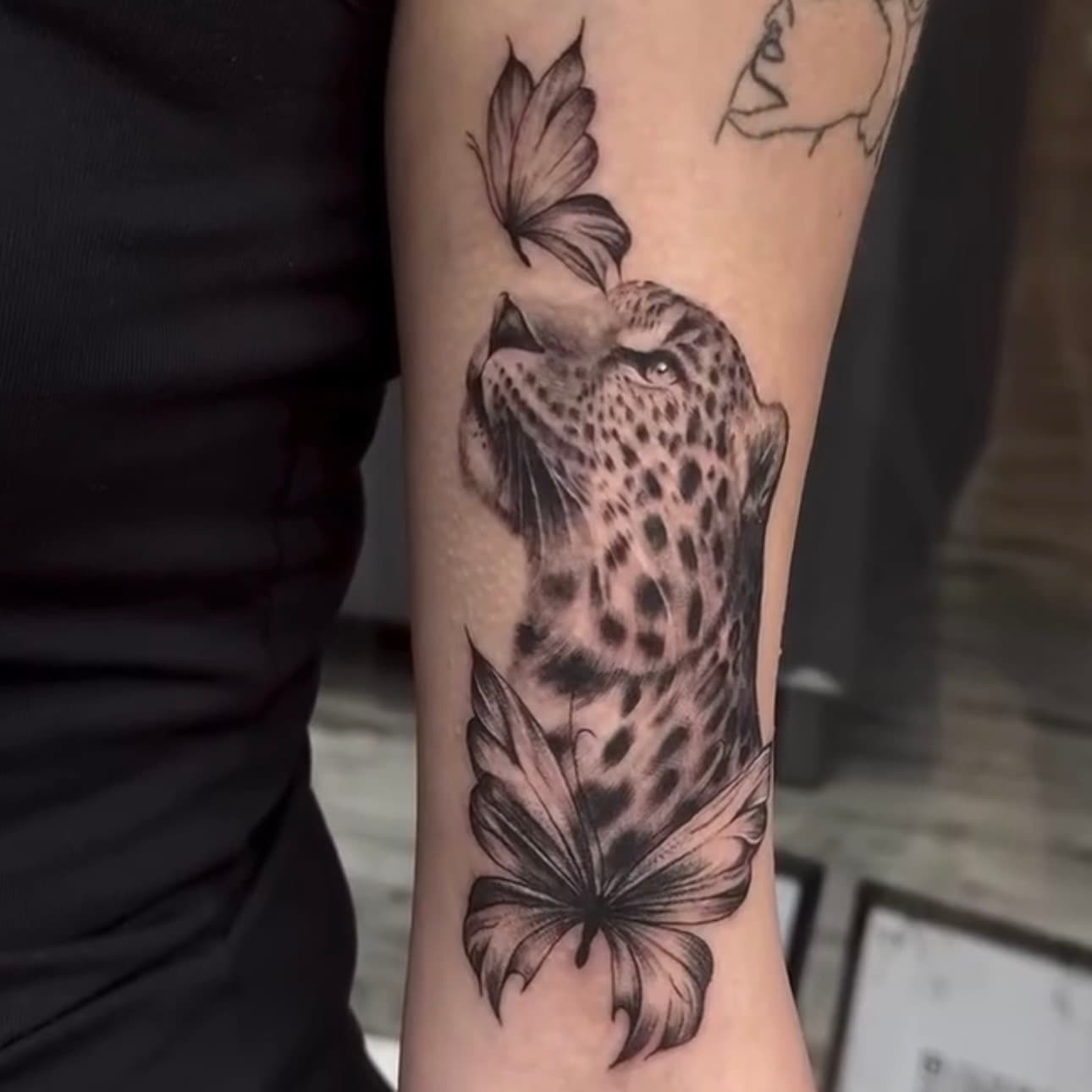 Tatuaje de leopardo en realismo con mariposa fineline, por Sara